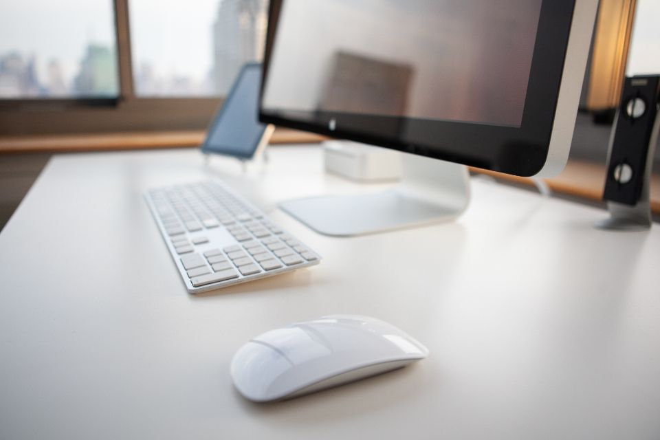 Bright home office desk with a computer, keyboard and mouse near a window
