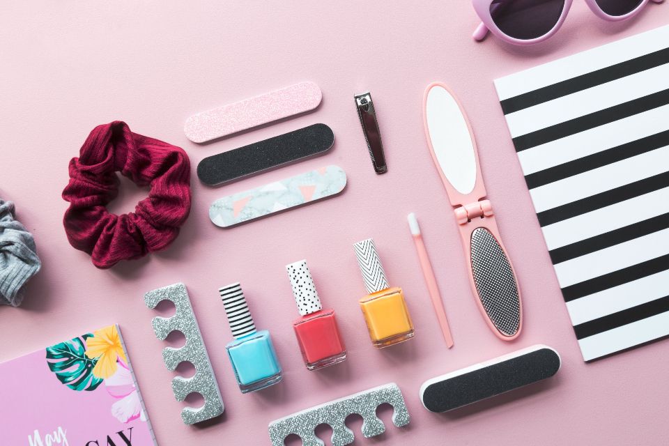 Flat lay of a scrunchie, nail polish and beauty accessories on a pink background