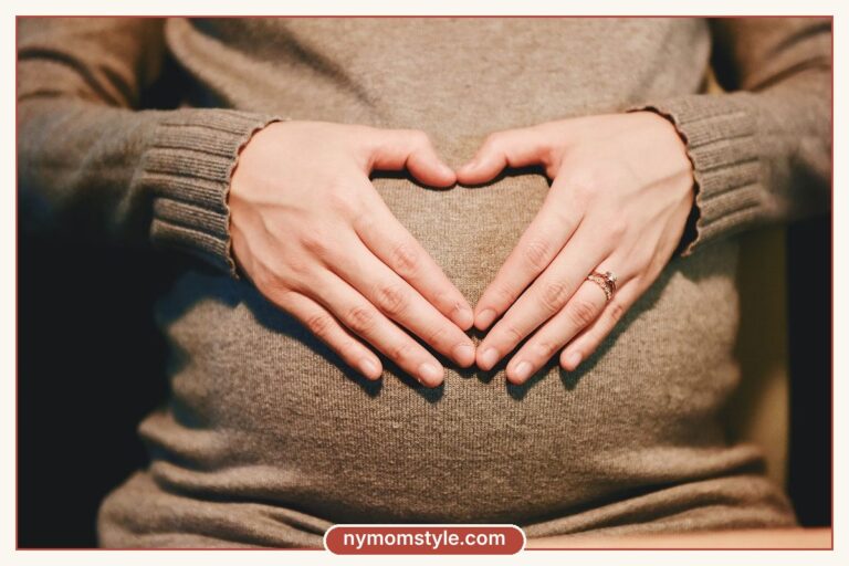 Hands forming a heart over the belly of a soft knit sweater, dressing a postpartum belly