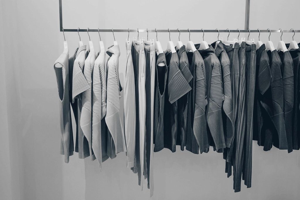 Minimal black and white photo of clothes hanging neatly on a rail