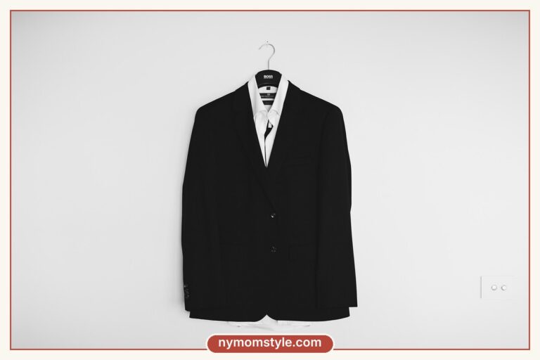 Black blazer on a hanger against a plain white wall, a minimalist wardrobe essential