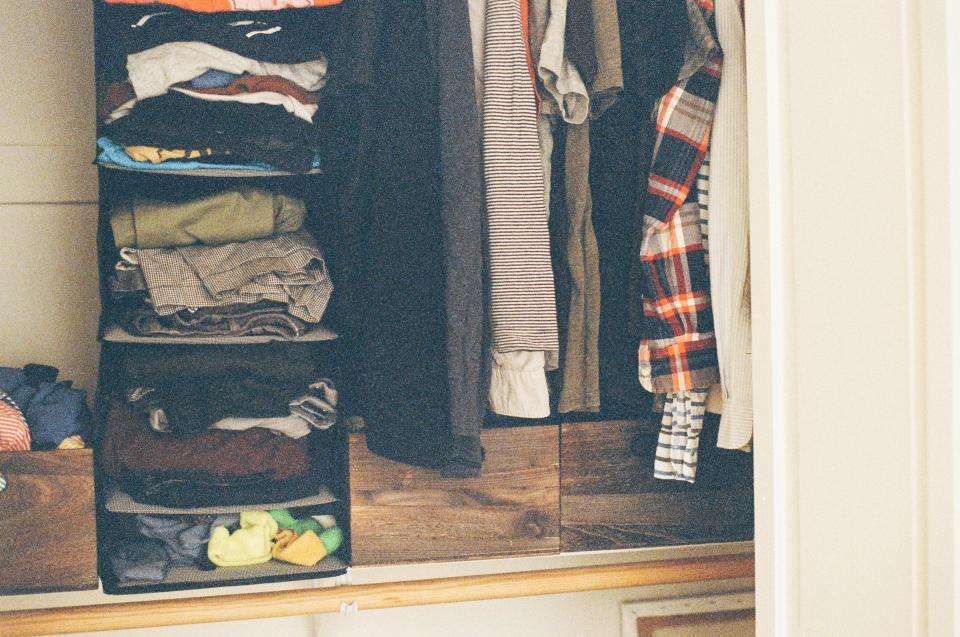 Open closet with folded and hanging clothes, ready to sort for a capsule wardrobe