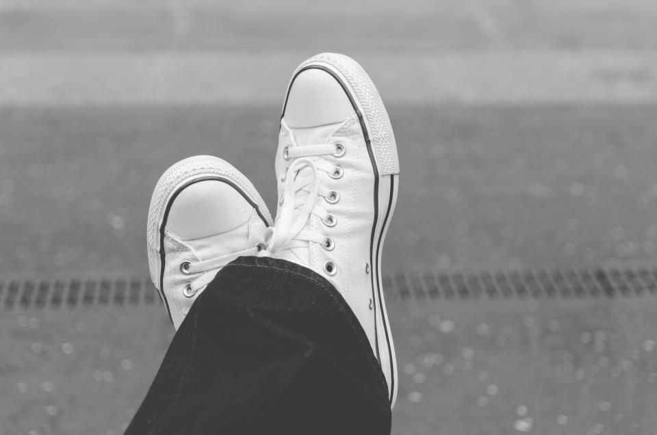 Pair of white canvas sneakers with crossed ankles, a classic everyday shoe