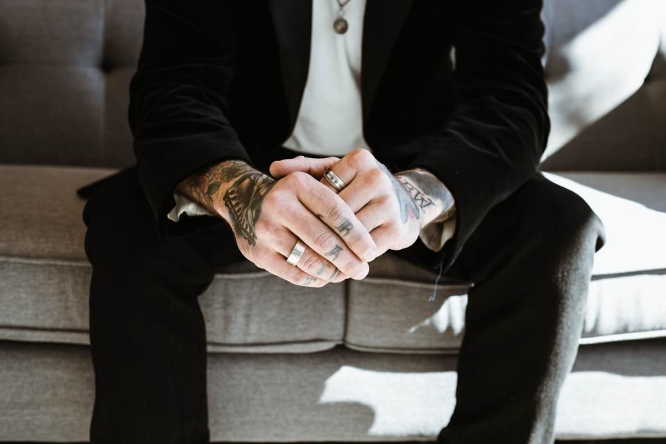 Person in a black blazer with hands clasped, a polished business casual look