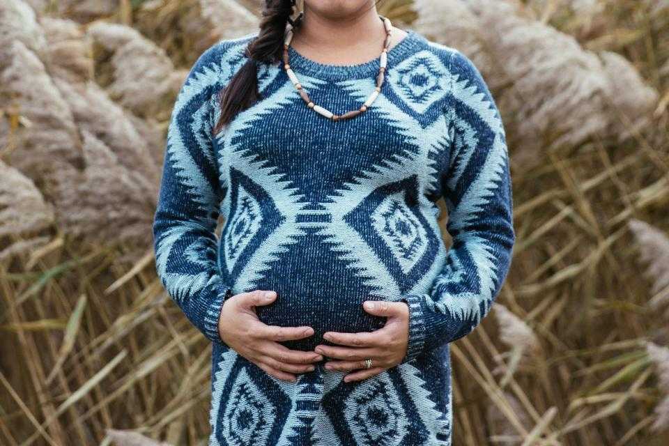 Soft patterned knit sweater worn over a rounded belly, comfortable styling for a changing midsection