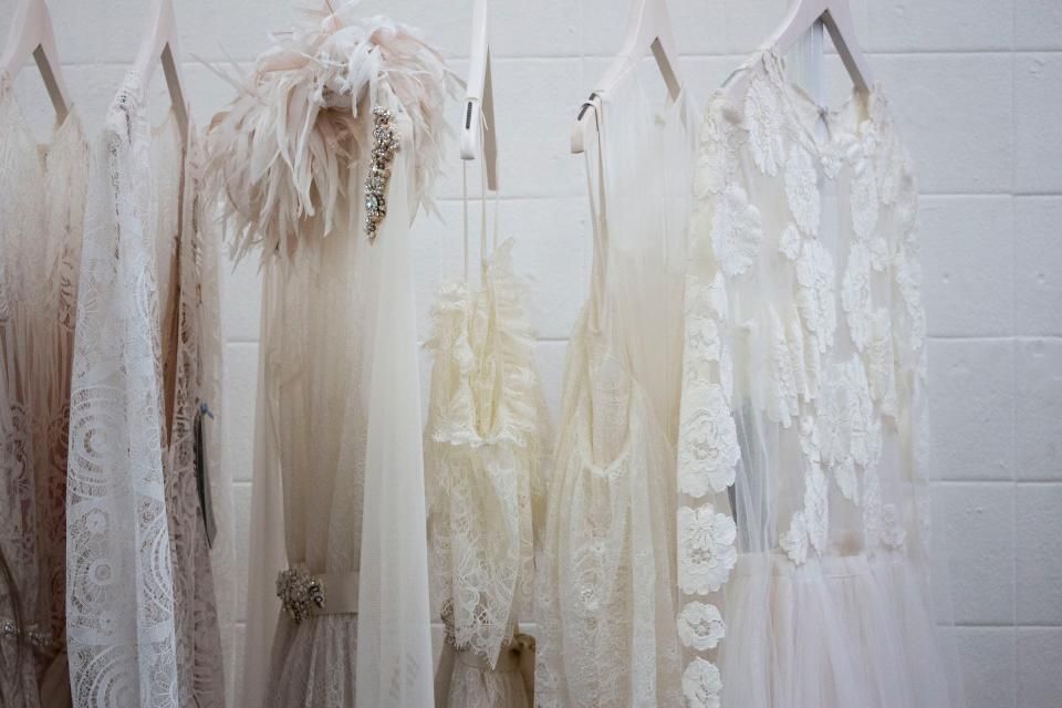 White dresses and tops hanging on a rail in soft light