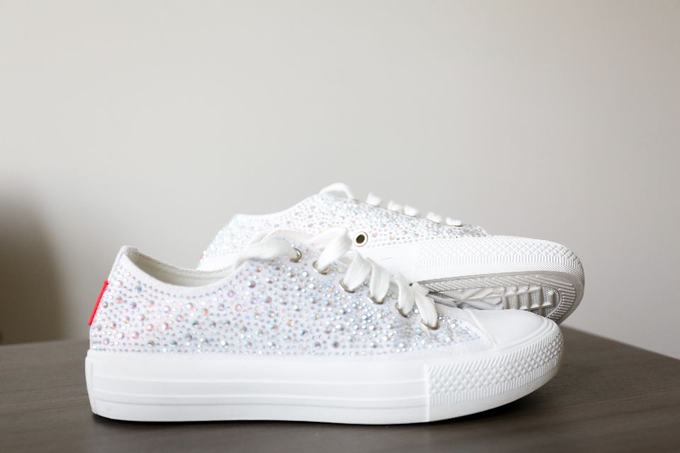 White low-top sneakers on a table, a neutral shoe that goes with many outfits